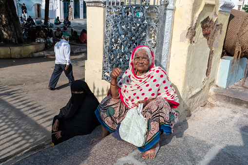 Hyderabad, India - September 2018: An elderly Indian women sitting beside the wall of the ancient Mecca Masjid in old Hyderabad.