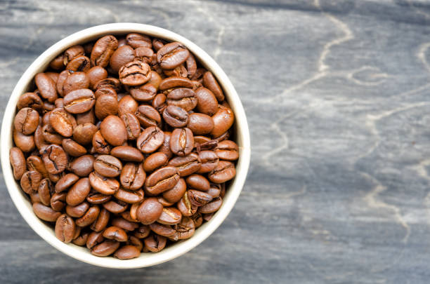 istock Roasted coffee beans in a paper cup on a black table. 1408048013