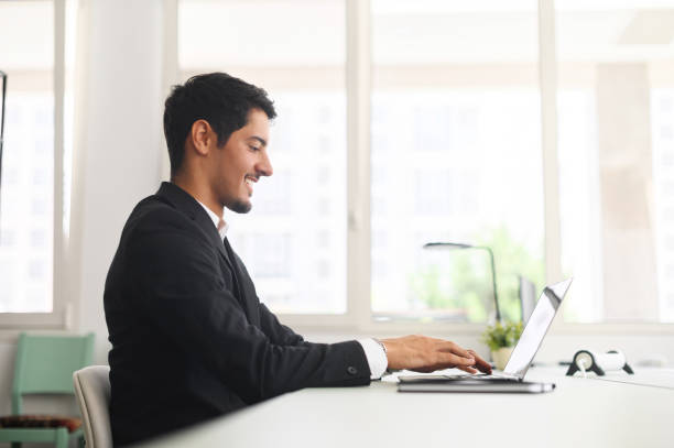 istock Optimistic hispanic male office employee using laptop in modern coworking space 1408049654