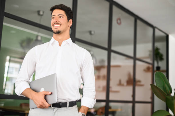 istock High-skilled smiling young businessman carrying laptop in a modern office 1408049708