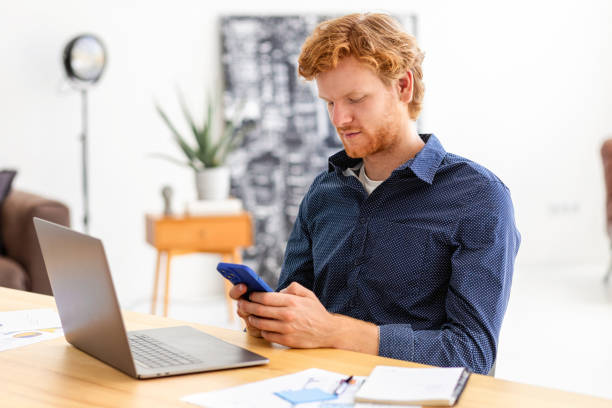istock Concentrated man entrepreneur freelancer sitting in modern office chatting using smartphone Young businessman, small business owner male working, writes message using mobile phone discussing something 1408049886