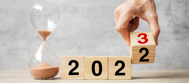 istock hand flipping block 2022 to 2023 text with hourglass on table. Resolution, time, plan, goal, motivation, reboot, countdown  and New Year holiday concepts 1408050421
