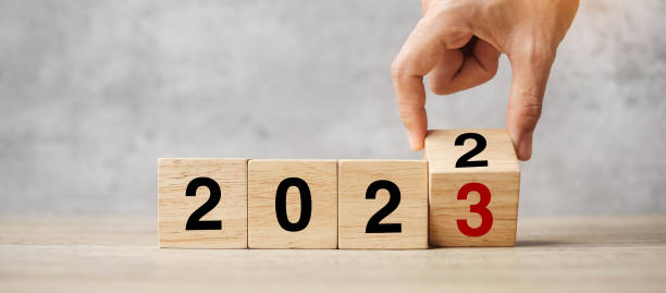 hand-flipping-block 2022 bis 2023 text in der tabelle. vorsatz, strategie, plan, ziel, motivation, neustart, business und neujahrsurlaubskonzepte - aiming challenge business throwing stock-fotos und bilder