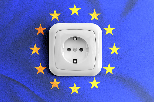 White socket with EU flag in the background. Concept of energy supply in the European area