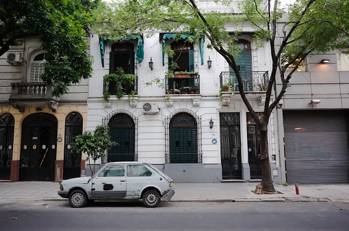 Buenos Aires, Argentina - January, 2020: Small car Renault 5 with traces of putty on car body parked along street in front of old houses. White car with body repair in front of house with white facade