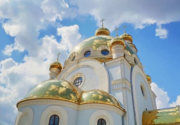 Beautiful Christian temple in the  Kharkiv city, Ukraine. White church building with golden domes. Blue sky with clouds. Architecture. Religious building stock photo