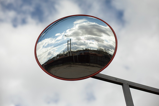 Round mirror. Reflector in parking lot. Mirror for safety. Reflective surface.