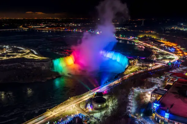 Photo of Horseshoe Falls winter illumination in twilight time. Niagara Falls City downtown horizon. Stunning landscape dusk to night.