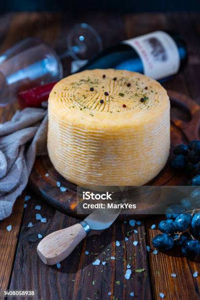 Big Head Of Cheese On A Cutting Board With Herbs And Blue Grapes Stock Photo - Download Image Now
