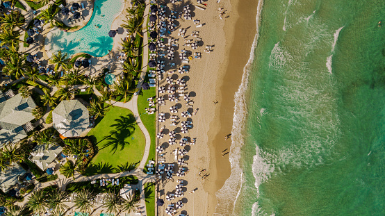 Aerial Drone View Directly Above a Beach Filled with Blue Beach Umbrella on the Sandy Shoreline in Palm Beach, Florida at Midday During the Spring of 2022