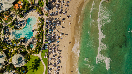 Vista aérea de drones directamente sobre una playa llena de sombrillas de playa azules en la costa de arena en Palm Beach, Florida al mediodía durante la primavera de 2022 photo