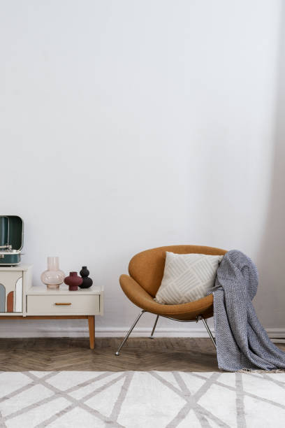 istock Orange armchair with plaid near sideboard against wall 1408060416