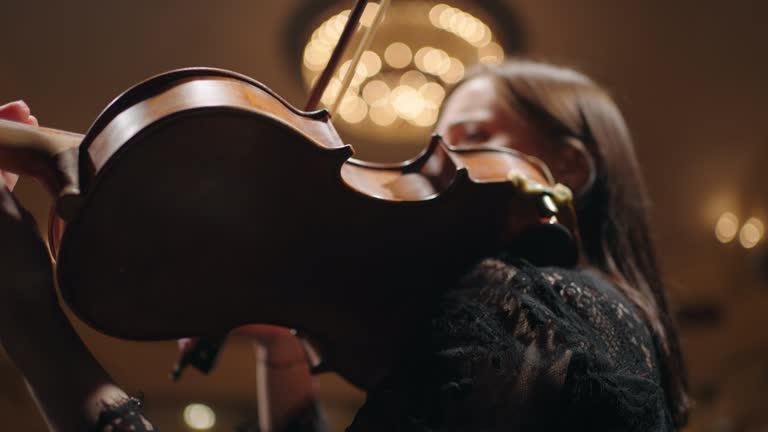 female violinist is playing music, closeup view of old expensive violin and female hands