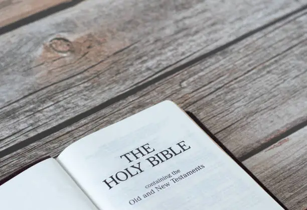 Open Holy Bible book containing the Old and New Testament on a rustic wooden table with copy space. A close-up. Studying the Word of God Jesus Christ. Christian biblical concept.
