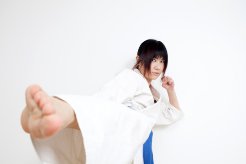 young woman practicing a karate kick.