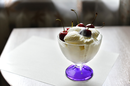 Creamy sweet ice cream in a glass ice cream maker with large cherry berries. Isolated object.