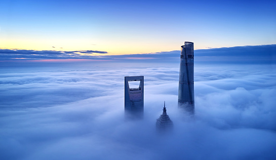 Drone point view of Shanghai landmark building on thick cloud at dawn, China.