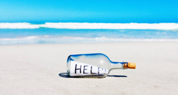 美しい海岸線の瓶に入ったキャスタウェイのメッセージには、助けを求めるメモが記されている。 - message in a bottle beached bottle desert island ストックフォトと画像