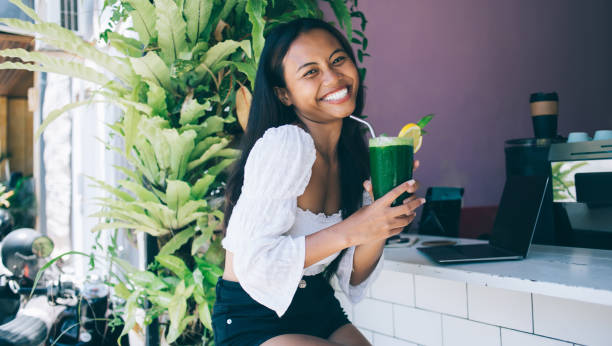 istock Joyful young Asian woman with refreshing drink in cafe 1408067845