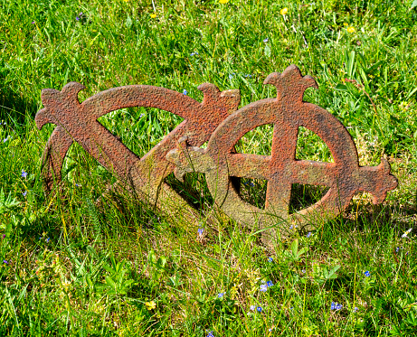 Two rusty iron grave markers in the churchyard of St Mary’s, in Kersey, Suffolk, Eastern England, on a sunny day in springtime.