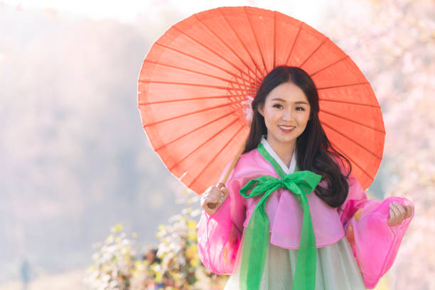 분홍색 우산을 쓰고 한복을 입은 한국 소녀. 한국 구시가지서울에서 전통 한복을 입은 아름다운 여성. - traditional clothing 뉴스 사진 이미지