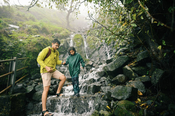 istock A young man helping a girl trekking through steps with flowing water during monsoon 1408069541