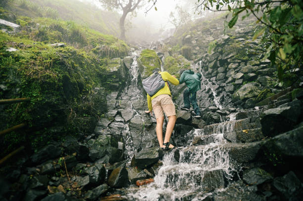 istock A young man assisting a girl trekking through steps with flowing water during monsoon 1408069567