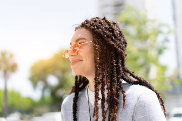 Women hipster with dreadlocks and pink sunglasses portrait outdoor side view. Close up headshot modern trendy female Women hipster with dreadlocks and pink sunglasses portrait outdoor side view. Close up headshot modern trendy female in city summer park dreadlocks stock pictures, royalty-free photos & images