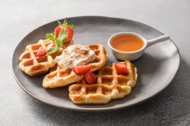 Photo of Trendy breakfast with croffles and morning coffee, strawberries. Croissant as waffle.