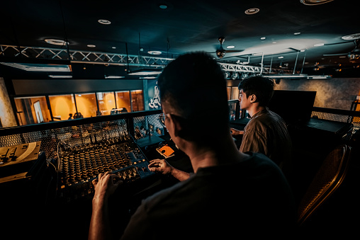 asian esports event crew working at backstage with control panel on stage lighting , sound system and lighting effect