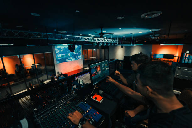 무대 조명, 사운드 시스템 및 조명 효과에 대한 제어판이있는 무대 뒤에서 일하는 아시아 스포츠 이벤트 승무원 - control room audio 뉴스 사진 이미지