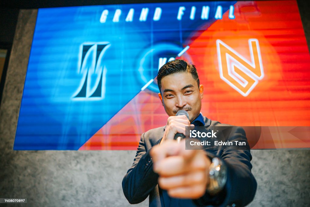 Asian Chinese Emcee Esports game show Host introducing grand final video game competition on stage with background projector screen Emcee Stock Photo