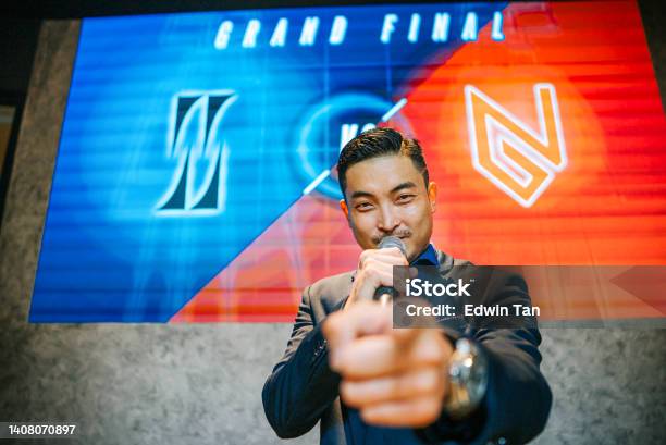Asian Chinese Emcee Esports Game Show Host Introducing Grand Final Video Game Competition On Stage With Background Projector Screen Stock Photo - Download Image Now