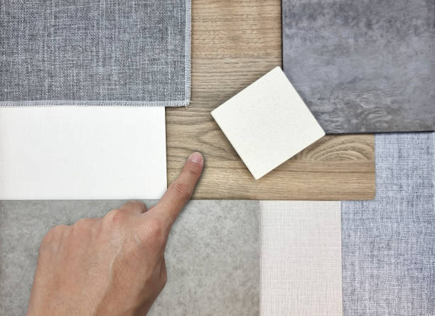 istock designer's hand selecting interior material samples board contains white grainy quartz, cement spc vinyl flooring, grey canvas fabric, oak wooden laminated. interior mood and tone board. 1408071378