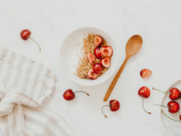 Healthy breakfast with greek yogurt, granola and cherry on bright white background