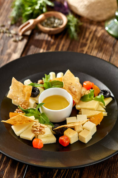 istock Cheese platter on wooden background in rustic style. Appetizer for wine - georgian cheese with honey. Cheese platter on black plate on wooden table. 1408071498