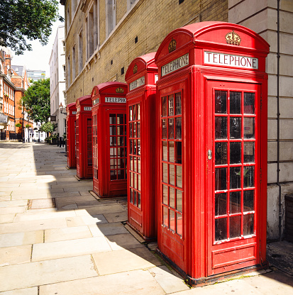 A group of five old fashioned red British phone boxes on a street in central London, England.