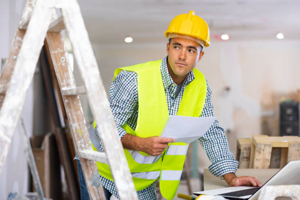 istock Engineer with drawings in his hands, checks the house reconstruction plan on a laptop 1408072884