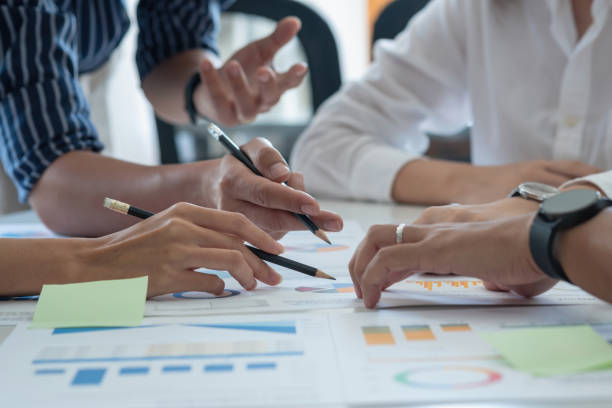 istock A team of businessmen plan with their laptops and graph charts for their profits and use a calculator to calculate their company's annual balance. 1408075331