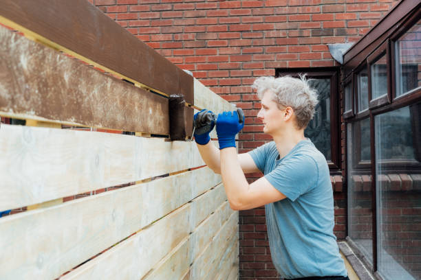 un jeune ouvrier peint avec un rouleau une clôture en bois dans le jardin. diy, concept do it yourself. amélioration de la maison. rénovation et remise à neuf de la maison. mise au point sélective, espace de copie. - paint roller copy space action adult photos et images de collection