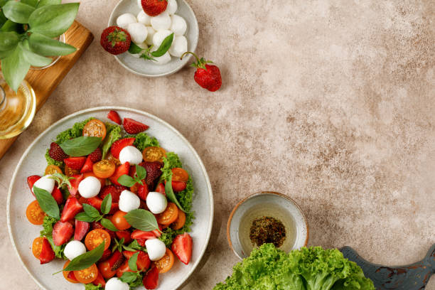 istock Dinner diet Dish, fresh salad with mozzarella cheese, cherry tomatoes, strawberry, basil on beige background. Healthy lunch, bright salat. 1408076577