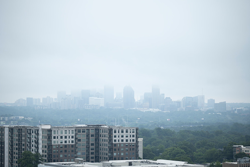 A foggy/misty summer morning after rainfall in Atlanta, Georgia, USA, viewed from a balcony on 22th floor in Buckhead. The image is part of a series of images of woodland and buildings captured with a full frame professional mirrorless digital camera and a sharp telephoto lens at low ISO (and f/2.8) resulting in large, clean images of professional quality. Minimal editing has been done to remove any trademarks and ensure that the light and atmosphere of the situation is correct. Not a rainy night in Georgia, but a foggy morning…