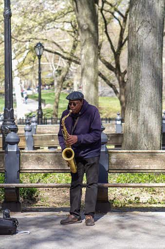 New York, NY - April 25 2022:  African American male playing a saxophone in Central Park