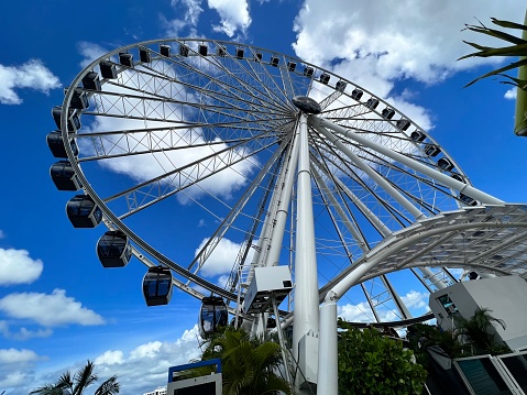 under the blue sky and white clouds ferris Wheel in Miami turns