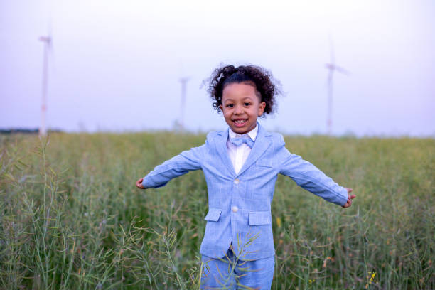 istock young black boy in blue suit standing in a field and spreading his arms 1408091929