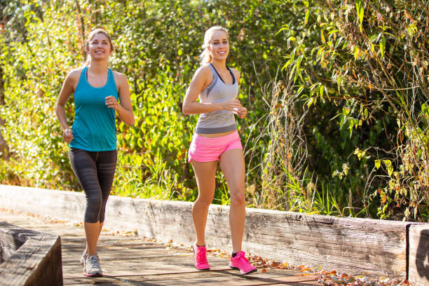 istock Female friends jogging outside together 1408093724