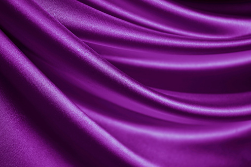 Bright purple silk satin. Soft wavy folds. Shiny silky fabric. Fuchsia color elegant background with space for design. Curtain. Drapery. Christmas, valentine, anniversary, party, celebration concept.