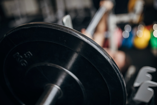 One man, fit man training with weights on bench press in gym.