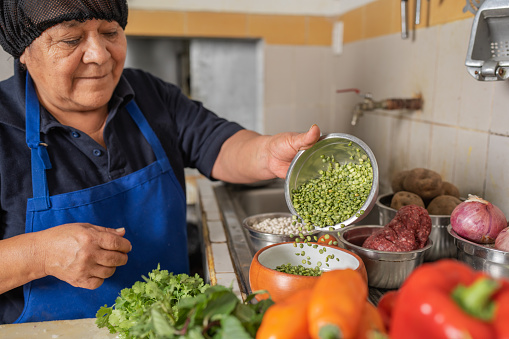 Latin american adult woman preparing ingredients for a ceviche in a restaurant kitchen