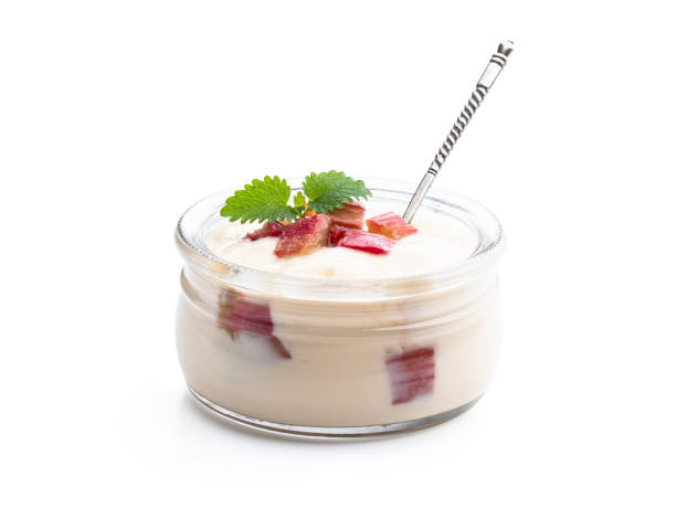 Delicious dessert is being served on a rustic wooden table, topped with berry sauce, an edible flower, and a sprig of mint